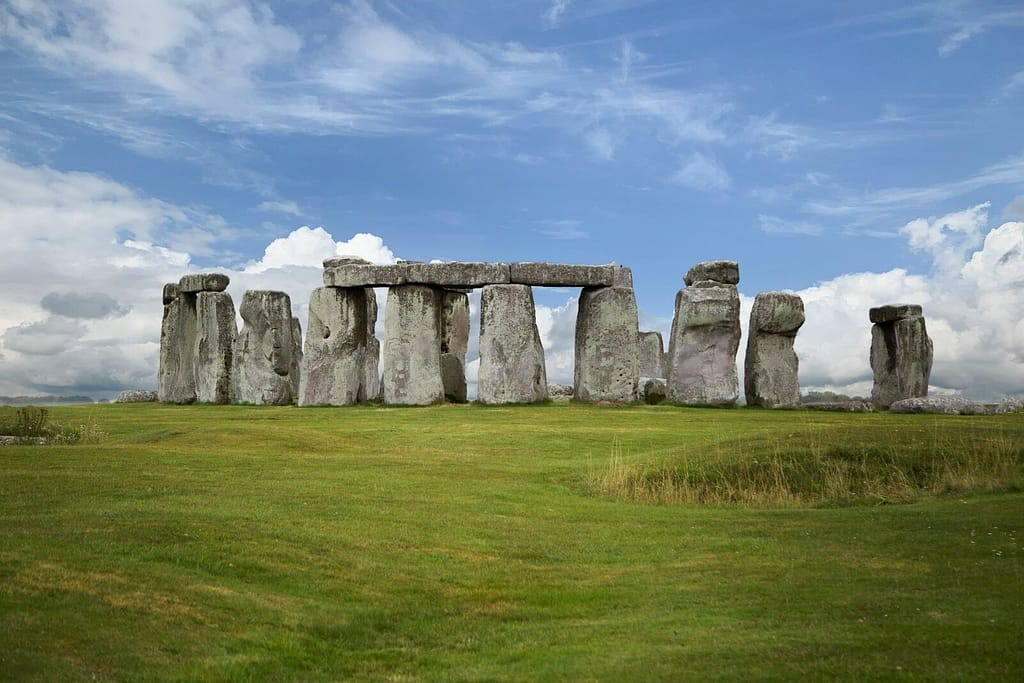 gray rock formation on green grass field under blue sky during daytime